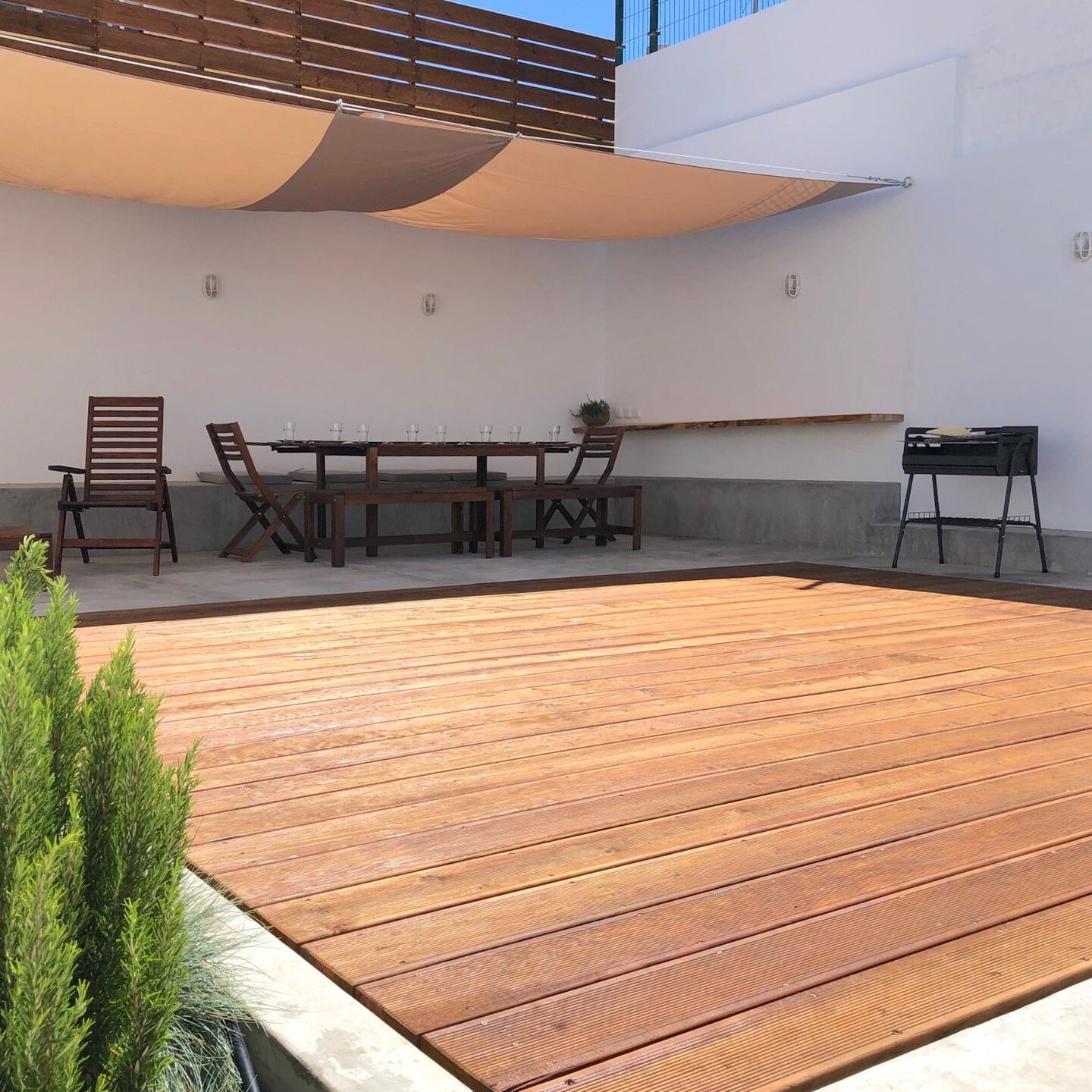 Wooden terrace with tables and chairs under a shaded cover, providing a relaxing outdoor space for guests’ stay.