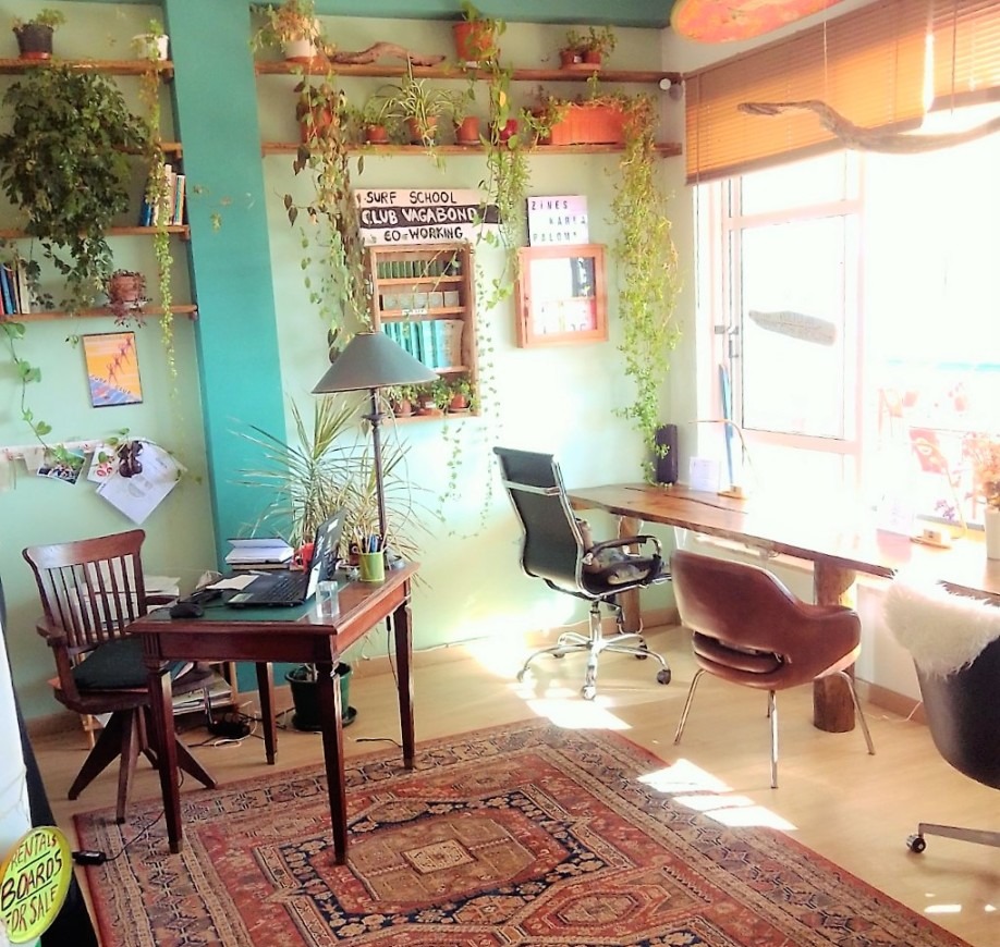 Sunlit Club Vagabond coworking space featuring desks and chairs arranged in front of large window screens.